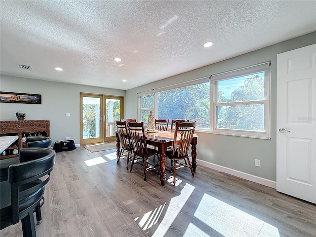 dining room featuring a textured ceiling, light wood-type flooring, and french doors