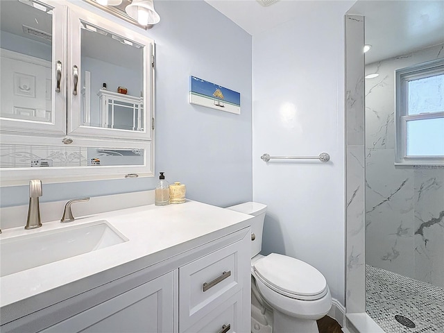 bathroom with vanity, toilet, and a tile shower