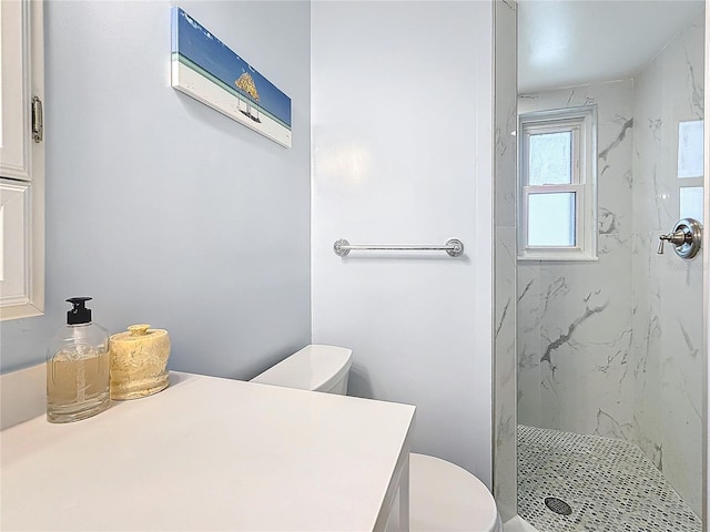 bathroom with tiled shower, vanity, and toilet