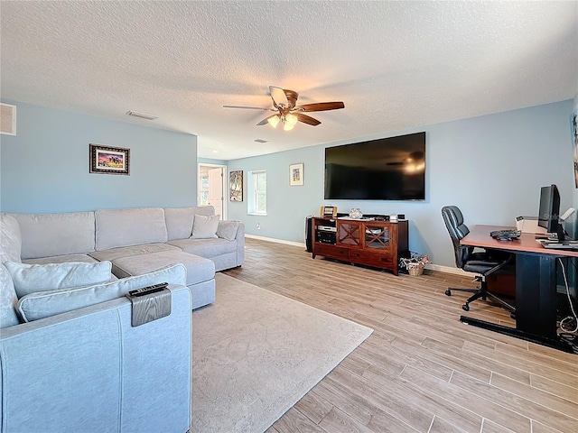 living room with a textured ceiling, ceiling fan, and light hardwood / wood-style flooring