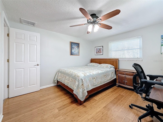 bedroom with ceiling fan, a textured ceiling, and light wood-type flooring