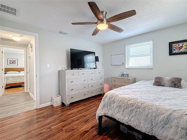 bedroom featuring ceiling fan, a textured ceiling, and dark hardwood / wood-style flooring