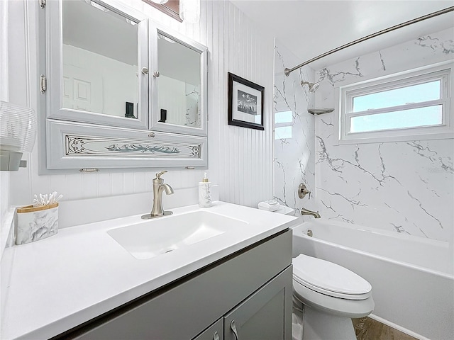 full bathroom featuring tiled shower / bath, vanity, and toilet