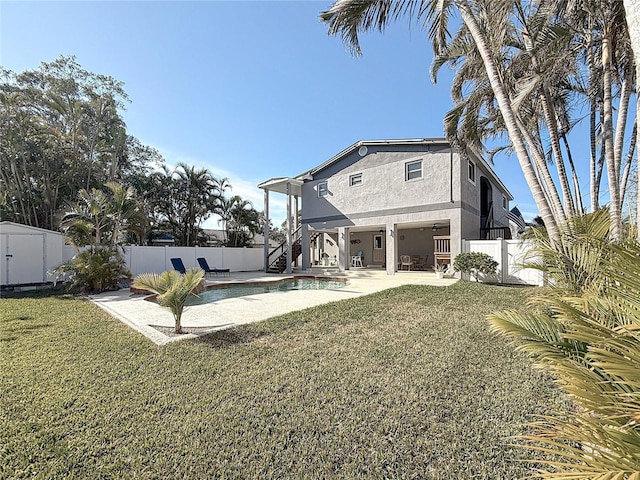 back of property with a fenced in pool, a patio area, ceiling fan, and a lawn