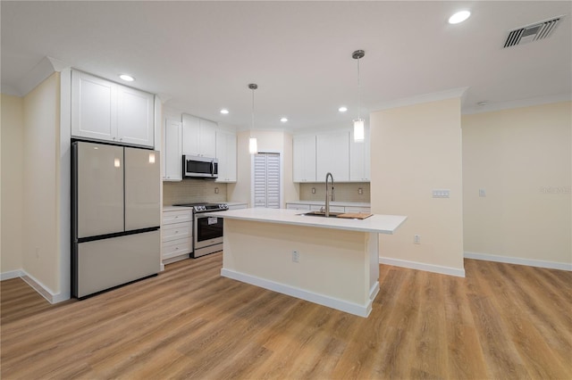 kitchen featuring appliances with stainless steel finishes, white cabinetry, tasteful backsplash, an island with sink, and decorative light fixtures