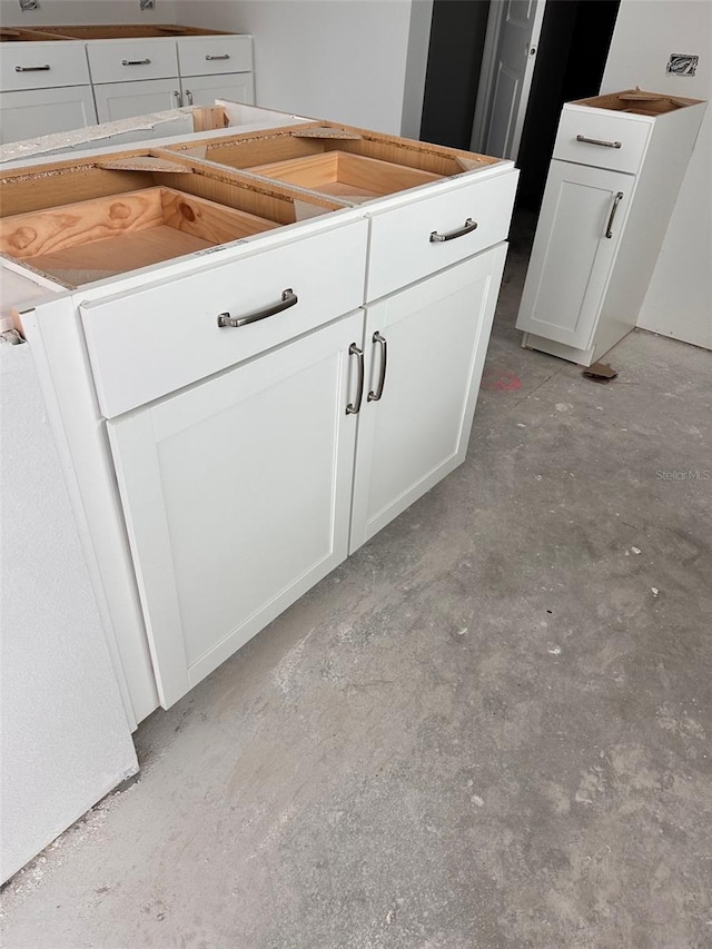 interior space featuring white cabinets and unfinished concrete flooring