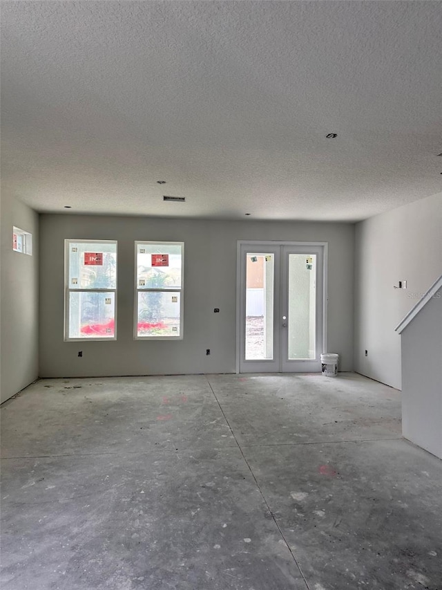 unfurnished living room featuring a textured ceiling and french doors