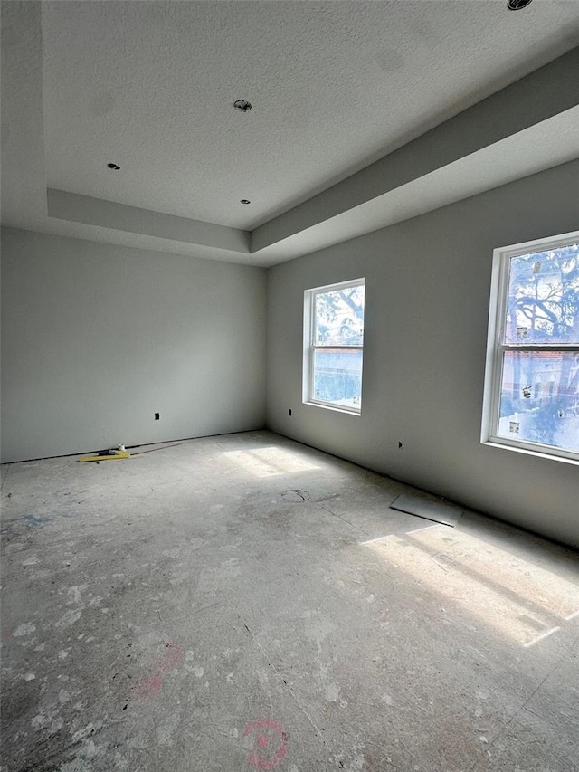 unfurnished room featuring a raised ceiling and a textured ceiling