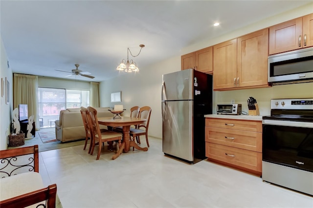 kitchen featuring stainless steel appliances, ceiling fan with notable chandelier, and hanging light fixtures