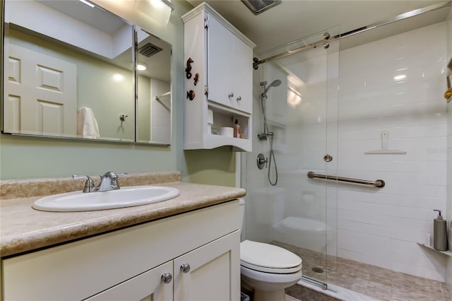 bathroom featuring vanity, a shower with door, and toilet