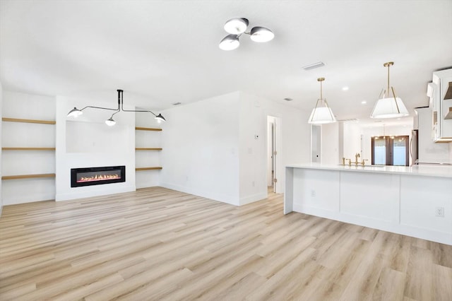 unfurnished living room featuring sink and light hardwood / wood-style floors