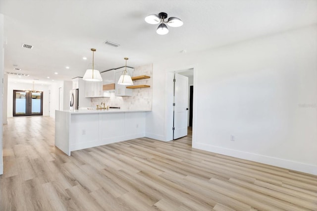 kitchen with backsplash, white cabinets, french doors, decorative light fixtures, and kitchen peninsula