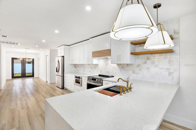 kitchen featuring tasteful backsplash, white cabinetry, decorative light fixtures, and stainless steel appliances