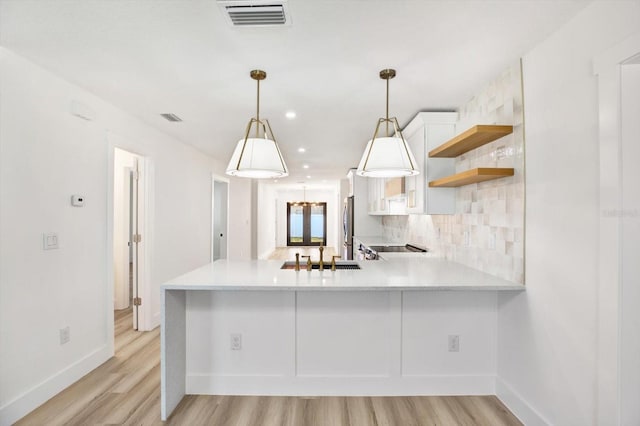 kitchen featuring sink, white cabinetry, backsplash, decorative light fixtures, and kitchen peninsula