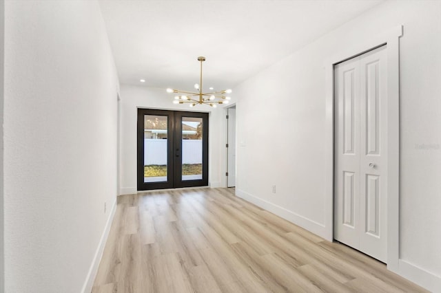 foyer entrance with a chandelier, light hardwood / wood-style floors, and french doors