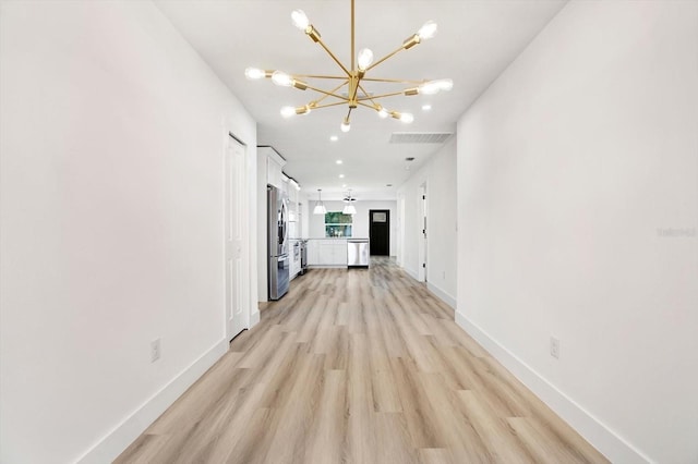 corridor with a chandelier and light wood-type flooring