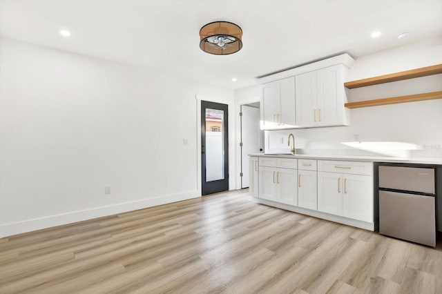 kitchen featuring sink, white cabinets, stainless steel refrigerator, and light hardwood / wood-style floors