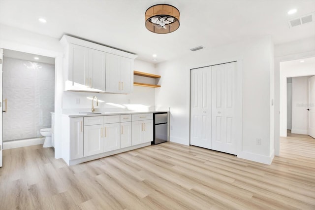 kitchen featuring white cabinetry, refrigerator, sink, and light wood-type flooring