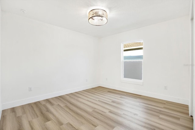 spare room with light hardwood / wood-style flooring and a notable chandelier