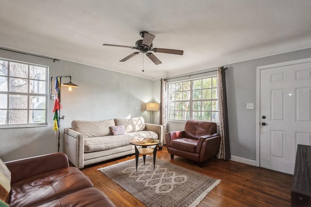 living room featuring dark wood-type flooring, ornamental molding, and ceiling fan