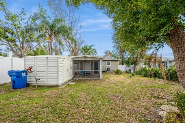 rear view of property with a sunroom, a shed, and a lawn