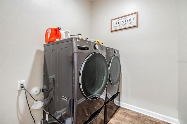 laundry room with hardwood / wood-style flooring and washing machine and clothes dryer