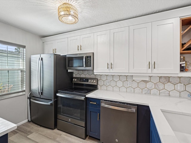 kitchen with blue cabinets, white cabinetry, sink, light stone counters, and stainless steel appliances