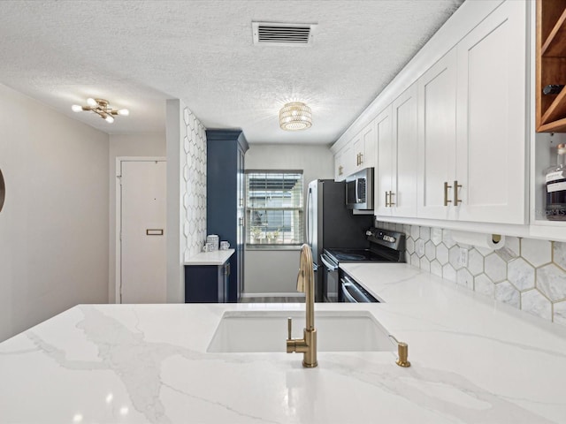 kitchen featuring electric stove, sink, light stone countertops, and white cabinets