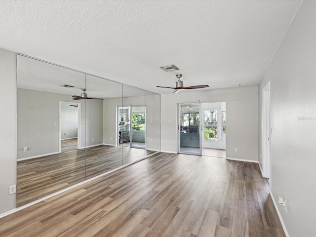 unfurnished room featuring ceiling fan, a textured ceiling, and light wood-type flooring