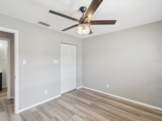 unfurnished bedroom featuring light wood-type flooring, ceiling fan, and a closet