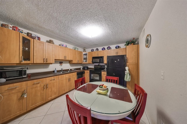 5557 Baywater Dr, Tampa, FL 33615 - kitchen with dark countertops, glass insert cabinets, light tile patterned flooring, a sink, and black appliances