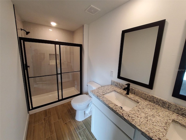 bathroom featuring vanity, a shower with shower door, and toilet