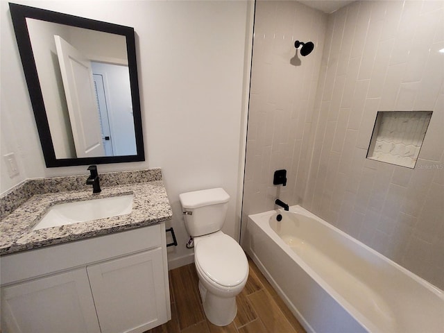 full bathroom featuring vanity, tiled shower / bath combo, and toilet