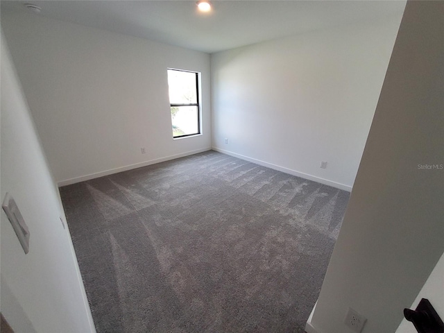 unfurnished room with dark carpet