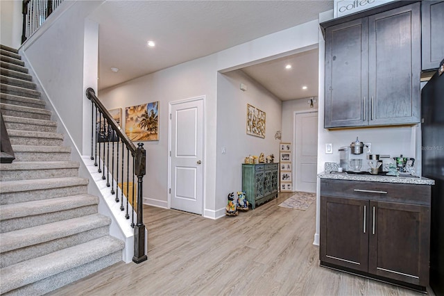 interior space with light hardwood / wood-style flooring, light stone counters, and dark brown cabinets