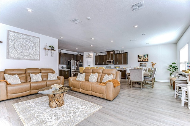 living room with light hardwood / wood-style flooring and a textured ceiling