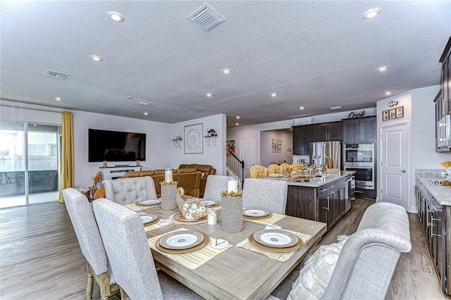 dining area with sink, light hardwood / wood-style flooring, and a textured ceiling