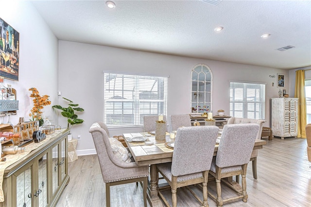 dining area featuring light hardwood / wood-style flooring and a textured ceiling