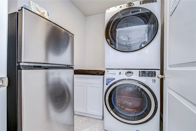 laundry area with stacked washer / drying machine and cabinets