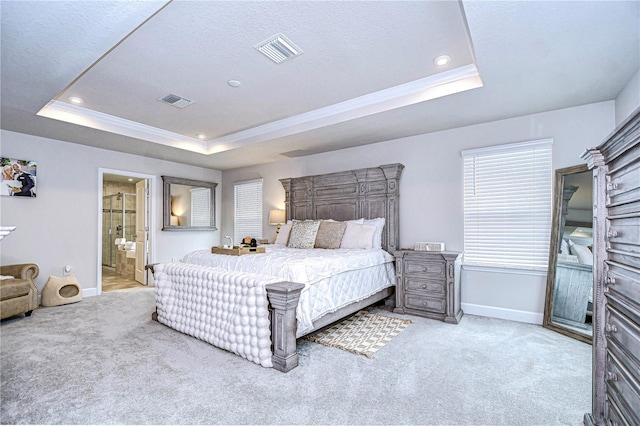 carpeted bedroom with crown molding, ensuite bath, and a tray ceiling