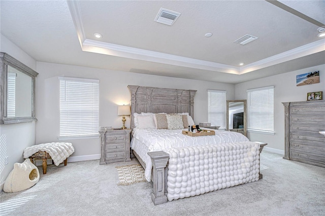 carpeted bedroom with crown molding and a tray ceiling