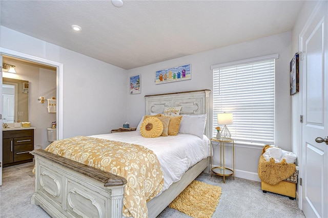 carpeted bedroom featuring multiple windows and ensuite bath