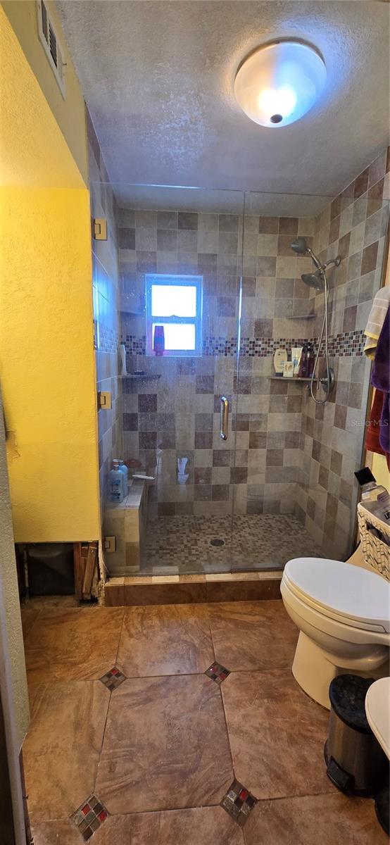 bathroom with toilet and an enclosed shower