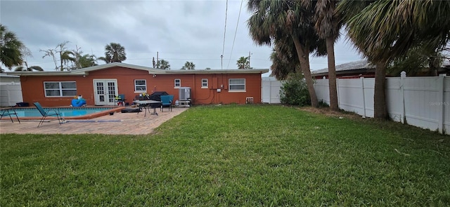 rear view of house with a patio, a covered pool, and a lawn