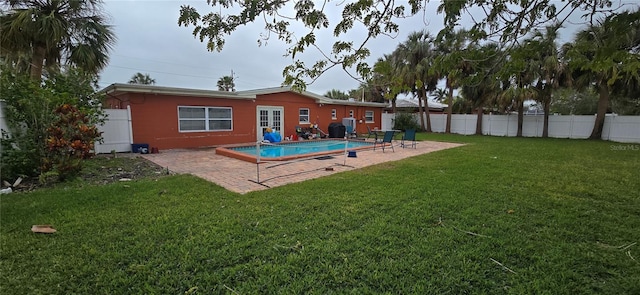 back of property with a fenced in pool, a lawn, and a patio