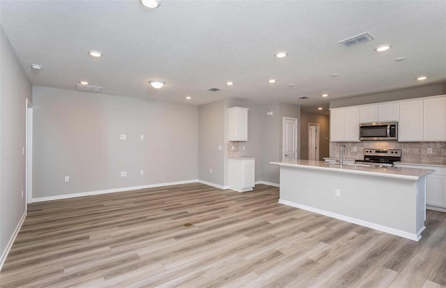 kitchen with white cabinetry, stainless steel appliances, and a kitchen island with sink