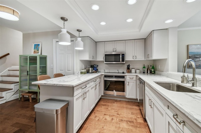 kitchen featuring appliances with stainless steel finishes, sink, pendant lighting, and kitchen peninsula