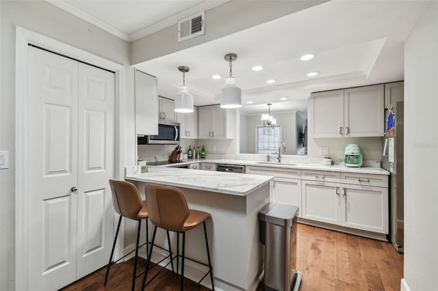 kitchen featuring a breakfast bar, hardwood / wood-style floors, pendant lighting, sink, and kitchen peninsula