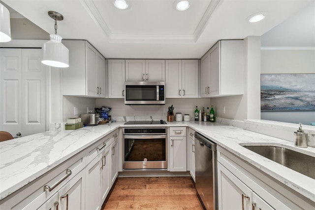 kitchen with light stone countertops, appliances with stainless steel finishes, a raised ceiling, and hanging light fixtures