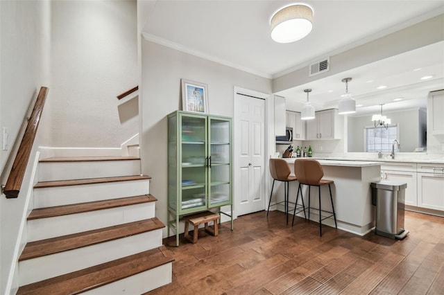 kitchen featuring sink, a breakfast bar, white cabinetry, dark hardwood / wood-style floors, and ornamental molding